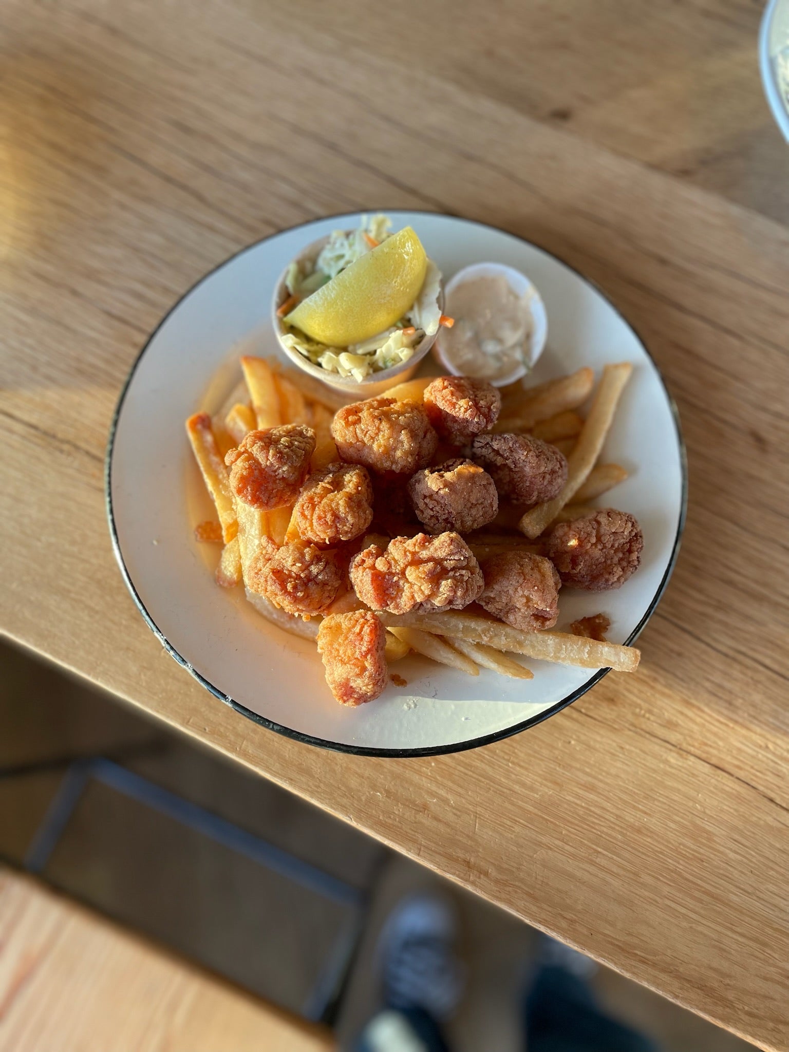 a white plate with fried scallops, fries, tartar, lemon
